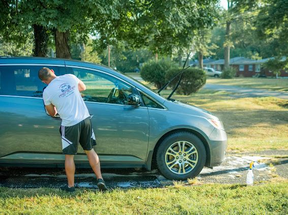 Detailer hand-washing a minivan at a customer's home