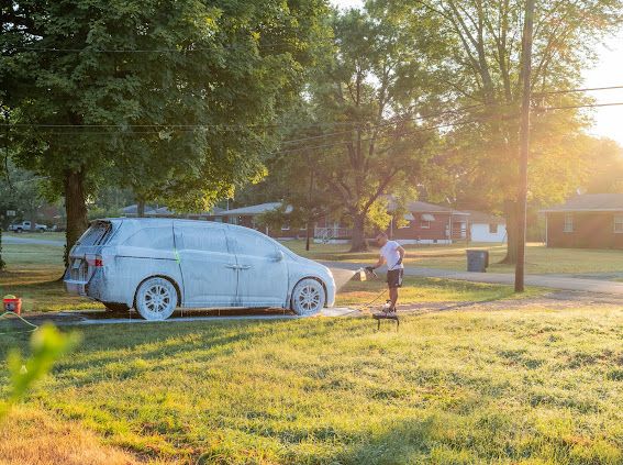 Minivan covered in thick foam during a golden hour mobile wash in Louisville