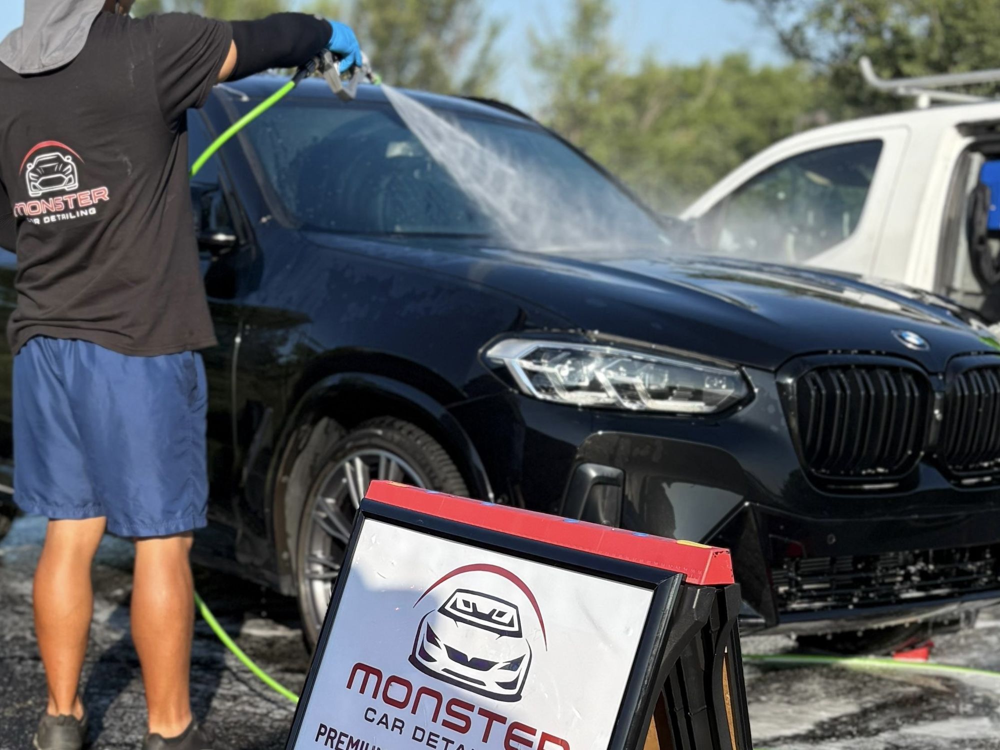 Monster Car Detailing technician foam-washing a black BMW X3 on site