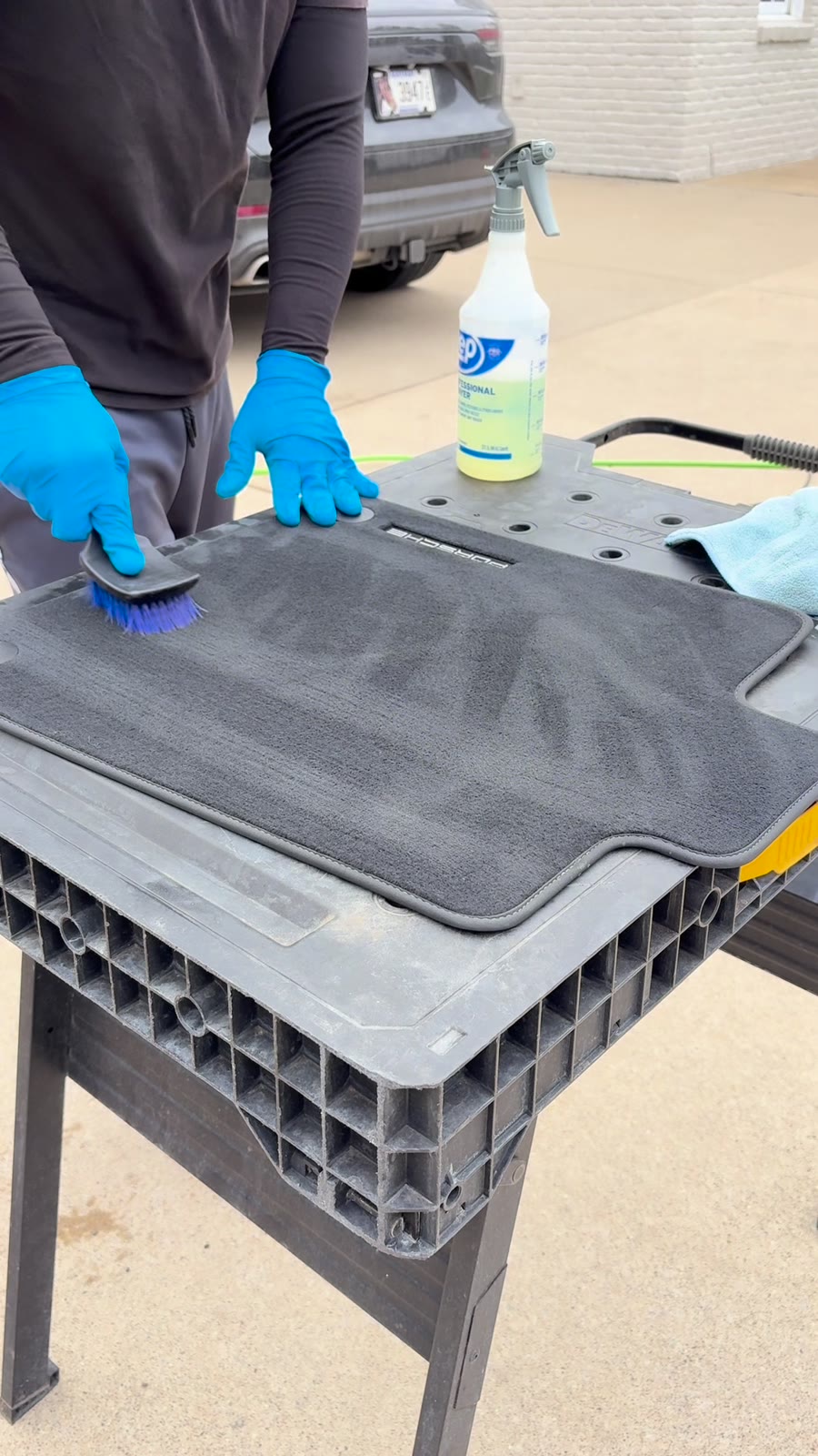 Detailer hand-scrubbing floor mats on a work station