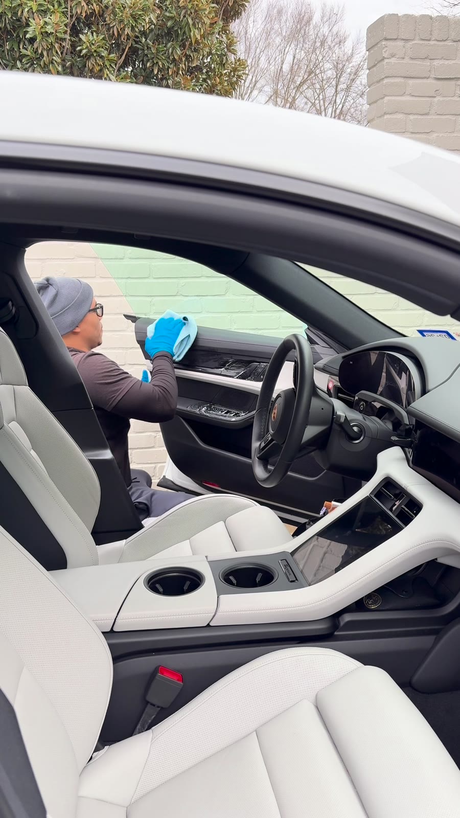 Detailer working on the interior of a Porsche Taycan through the open door